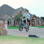 A boy on his bicycle in a heighborhood jumping off of a ramp
